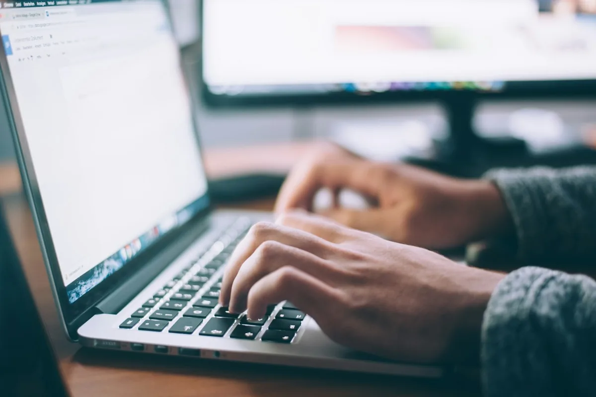 Persona trabajando con laptop y documentos en el escritorio